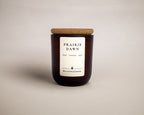 A dark amber glass jar candle with a cork lid and a white label reading 'PRAIRIE DAWN' and 'MEADOW & EMBER', centered on a light beige background.